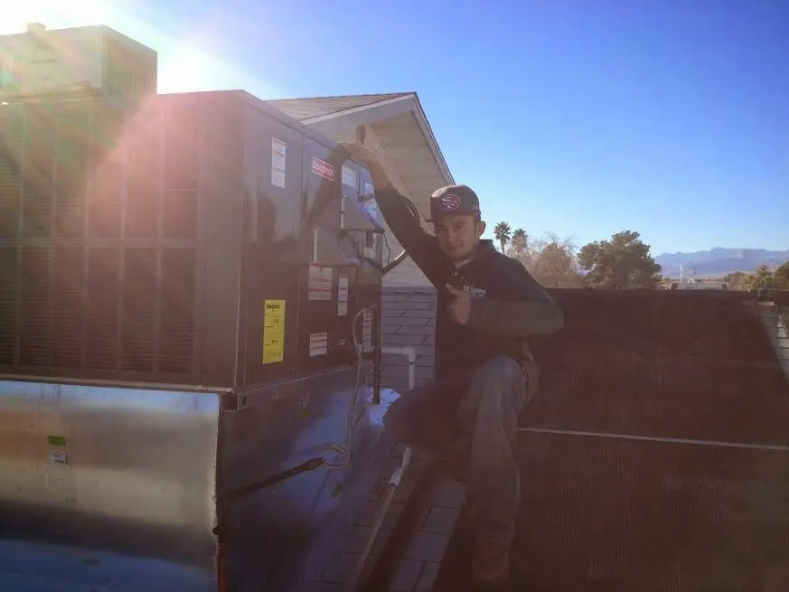HVAC technician performing Air Duct Cleaning on a rooftop unit in Lancaster